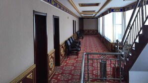 Un pasillo con alfombra roja, puertas de madera y una escalera con barandillas de metal.