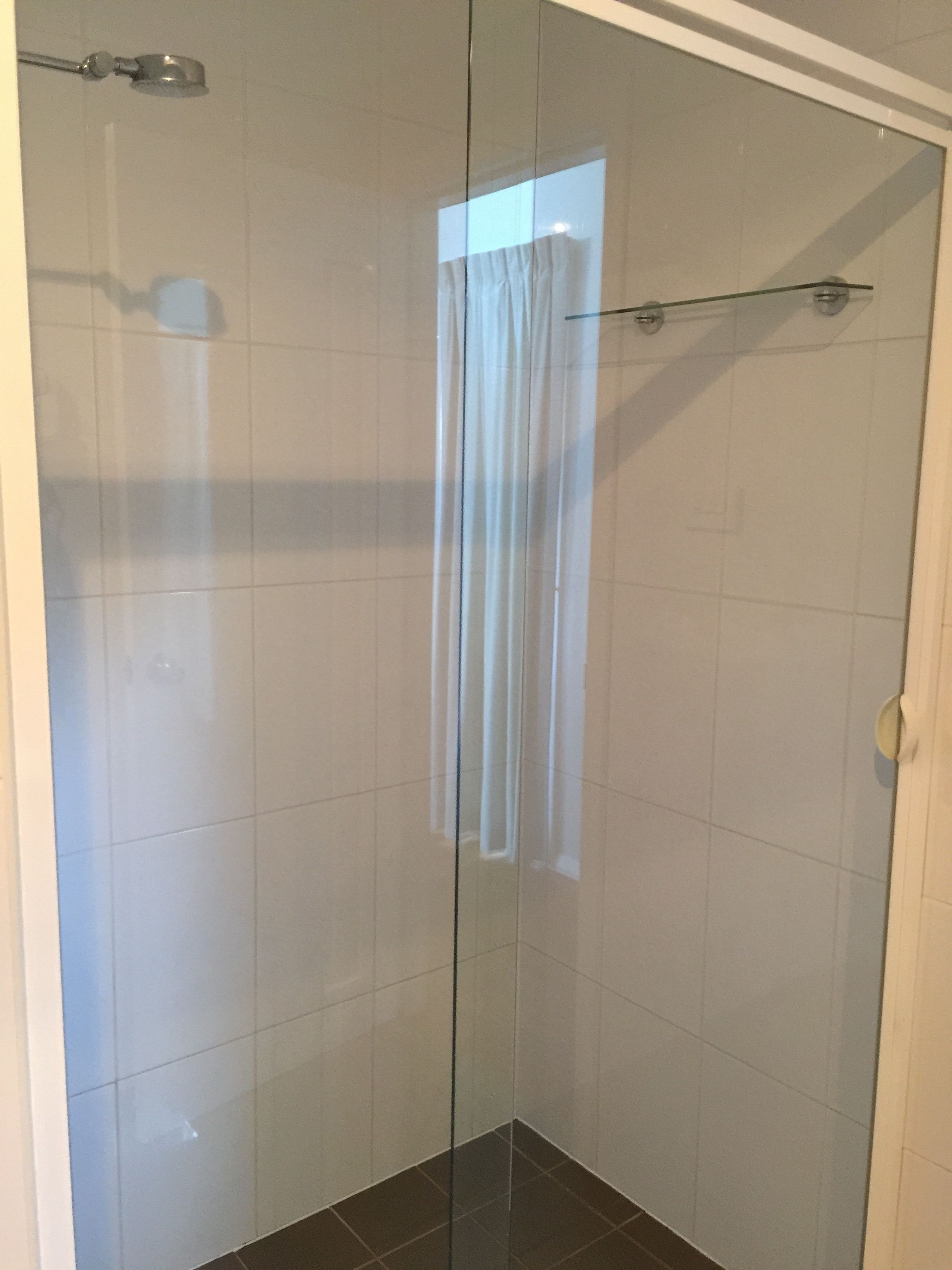 A glass-enclosed shower area with a curtain, tiled walls, and a visible showerhead.