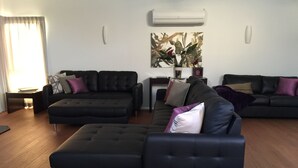 Een moderne woonkamer met een modulaire bank, een salontafel en een eethoek met een tafel en stoelen.