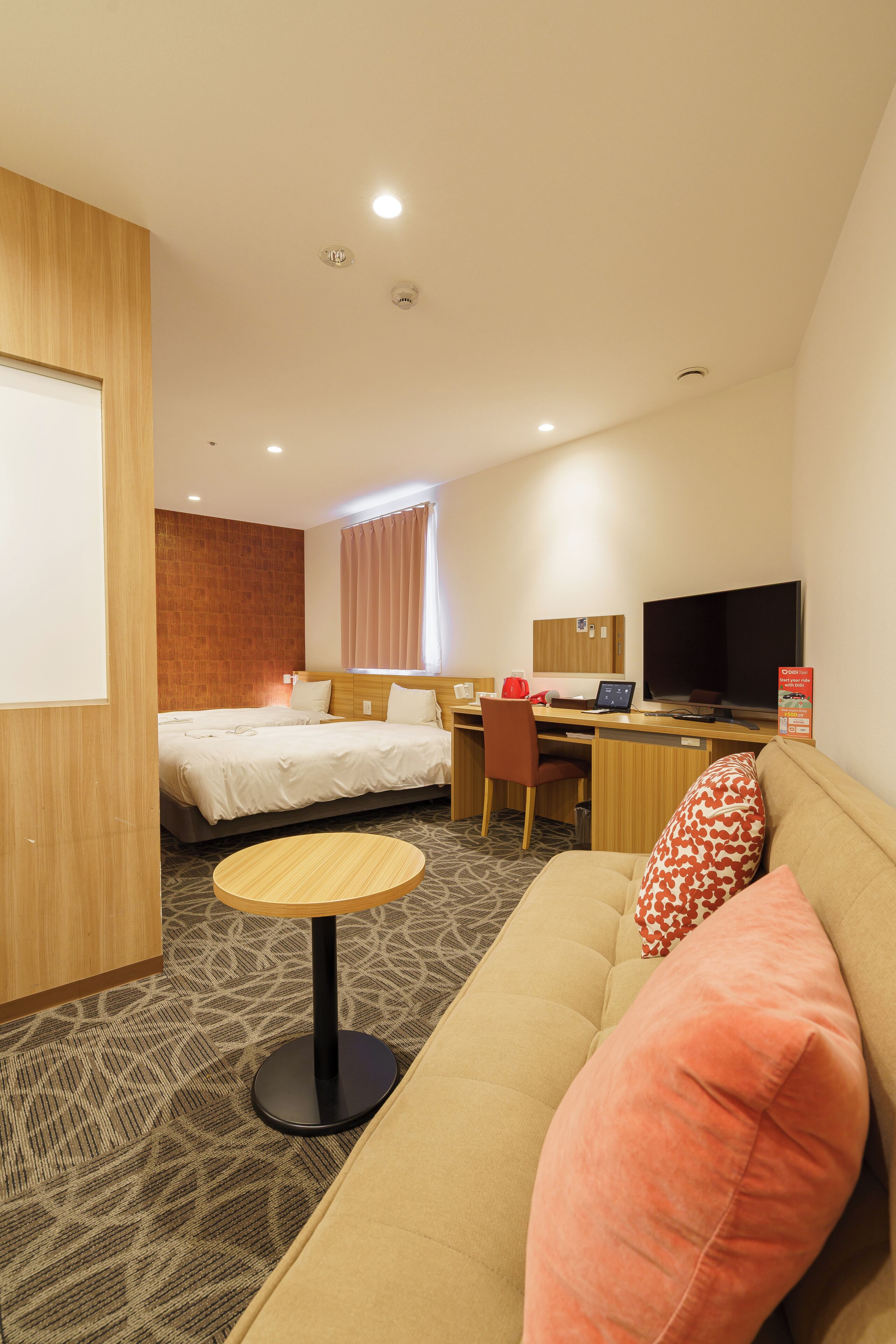 A hotel room with a bed, a desk, a television, a sofa, and a small table.
