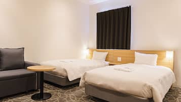 A hotel room with two beds, a sofa, a small round table, and a patterned carpet.