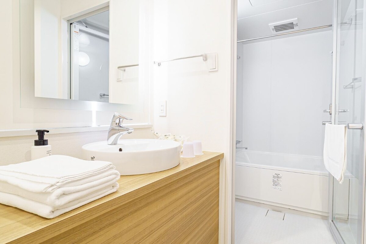 A bathroom with a sink, mirror, and shower.