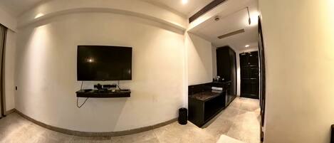 A modern living room with a flat-screen TV mounted on the wall, a dark console table, and a white sofa.
