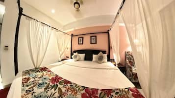 Un dormitorio con cama con dosel, colcha estampada y dos cuadros colgados en la pared.