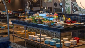 A buffet setup with various food items and a variety of plates and bowls.