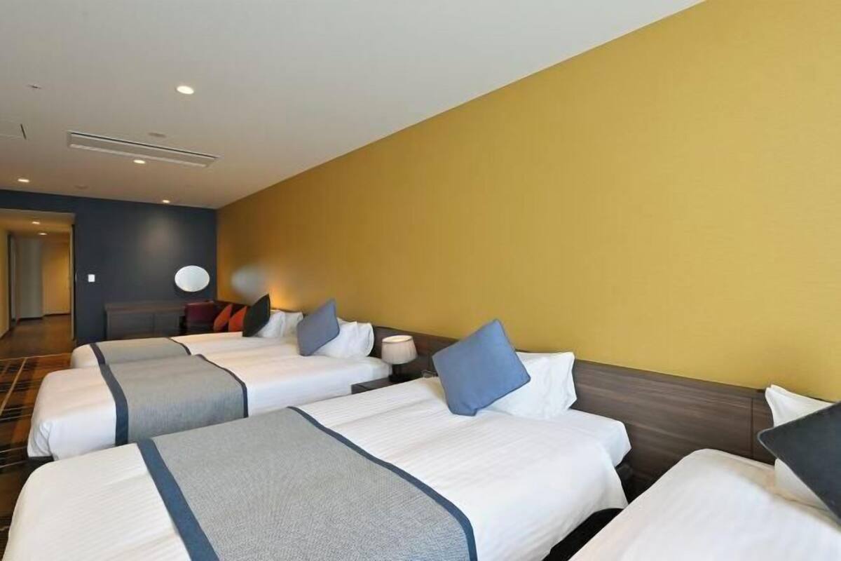 Ett hotellrum med fyra sängar, en rund väggklocka och en modern design.