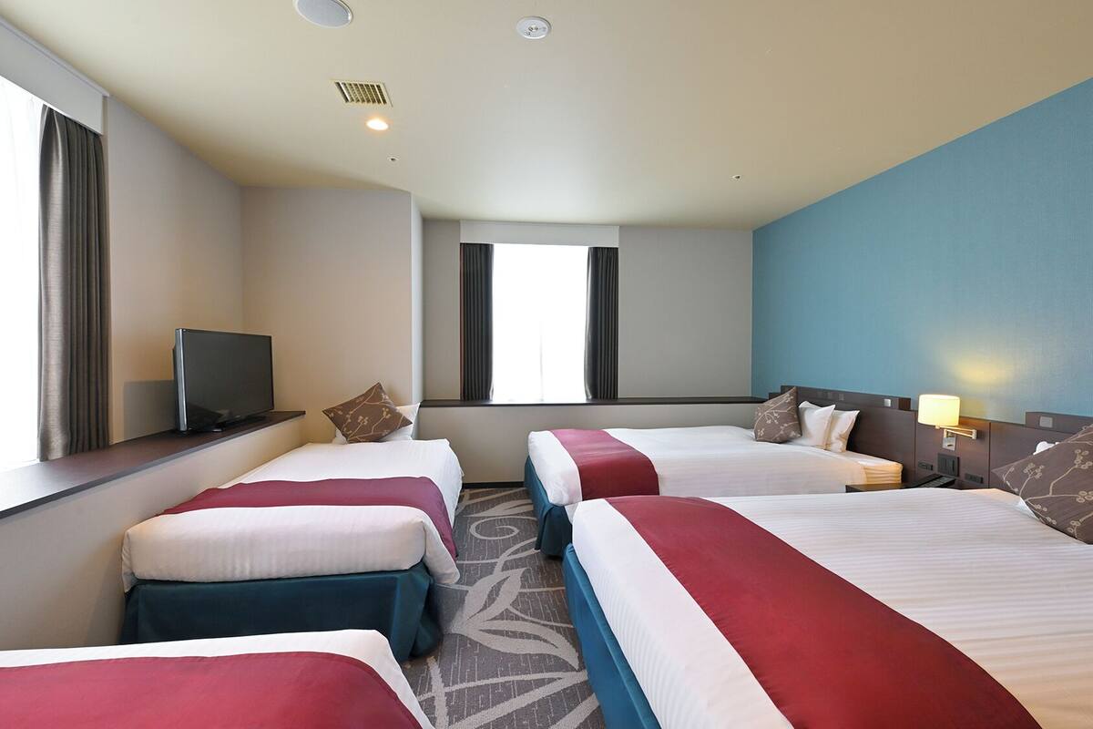 Ett hotellrum med två sängar, en TV och ett fönster med gardiner.