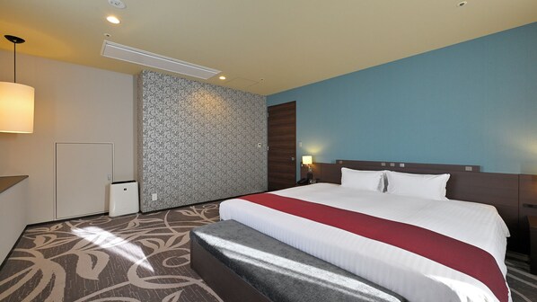 A hotel room with a large bed, a desk, a chair, a patterned carpet, and a wall with a floral design. - Quintessa Hotel Osaka Bay (Osaka)
