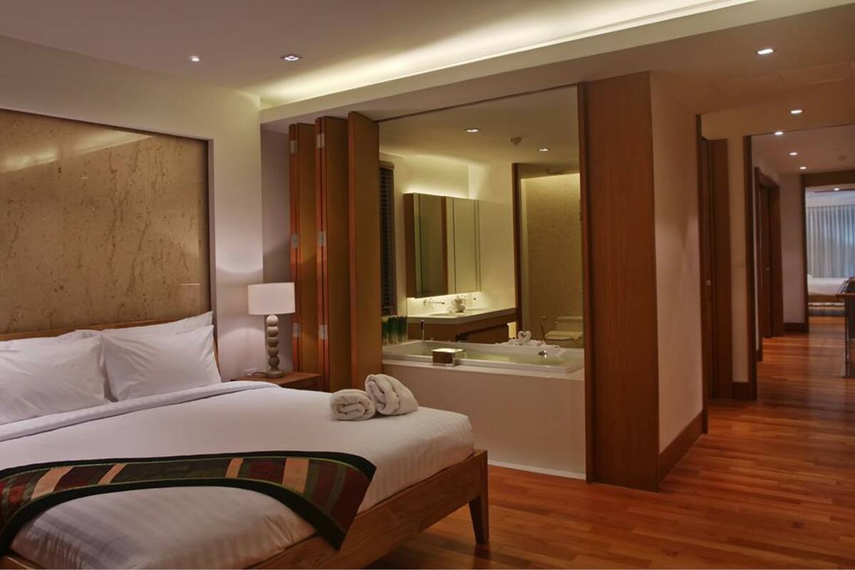 A hotel room with a large bed, a bathroom with a bathtub, and a mirror.
