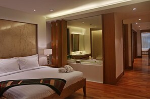 Une chambre d’hôtel avec un grand lit, une salle de bain avec une baignoire et un miroir.