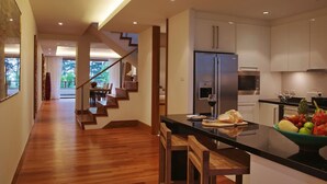 A modern kitchen with a central island, stainless steel appliances, and a dining area with wooden chairs. - The Pearl of Naithon (Sa Khu)