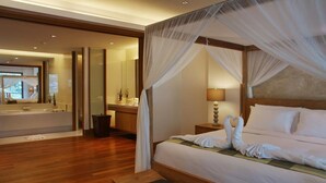 A spacious bedroom with a large bed, a bedside table, a nightstand, a wooden bench, a bathroom with a bathtub, and a mirror. - The Pearl of Naithon (Sa Khu)