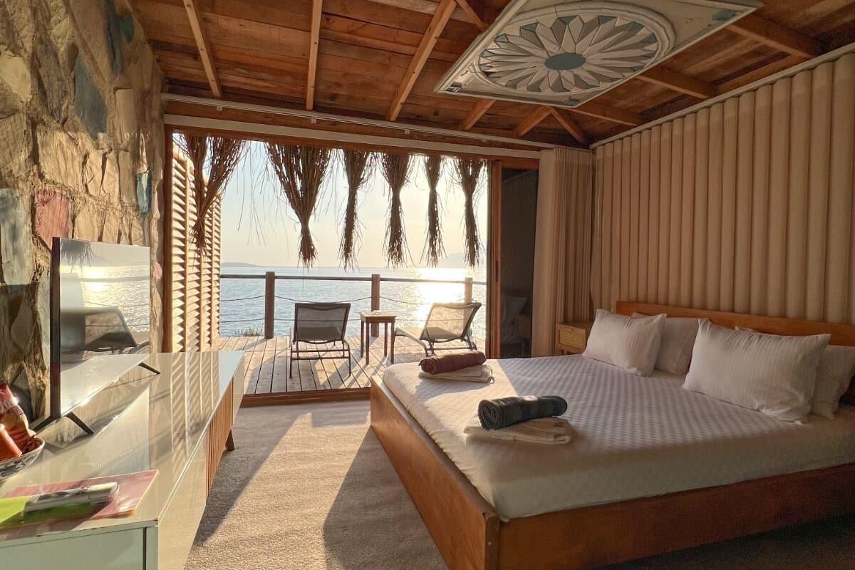 Un dormitorio con una cama grande, un escritorio y vista al mar.