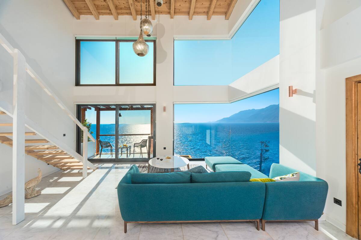 Amplia sala de estar con un sofá grande, una mesa de comedor y vistas al mar a través de grandes ventanales.