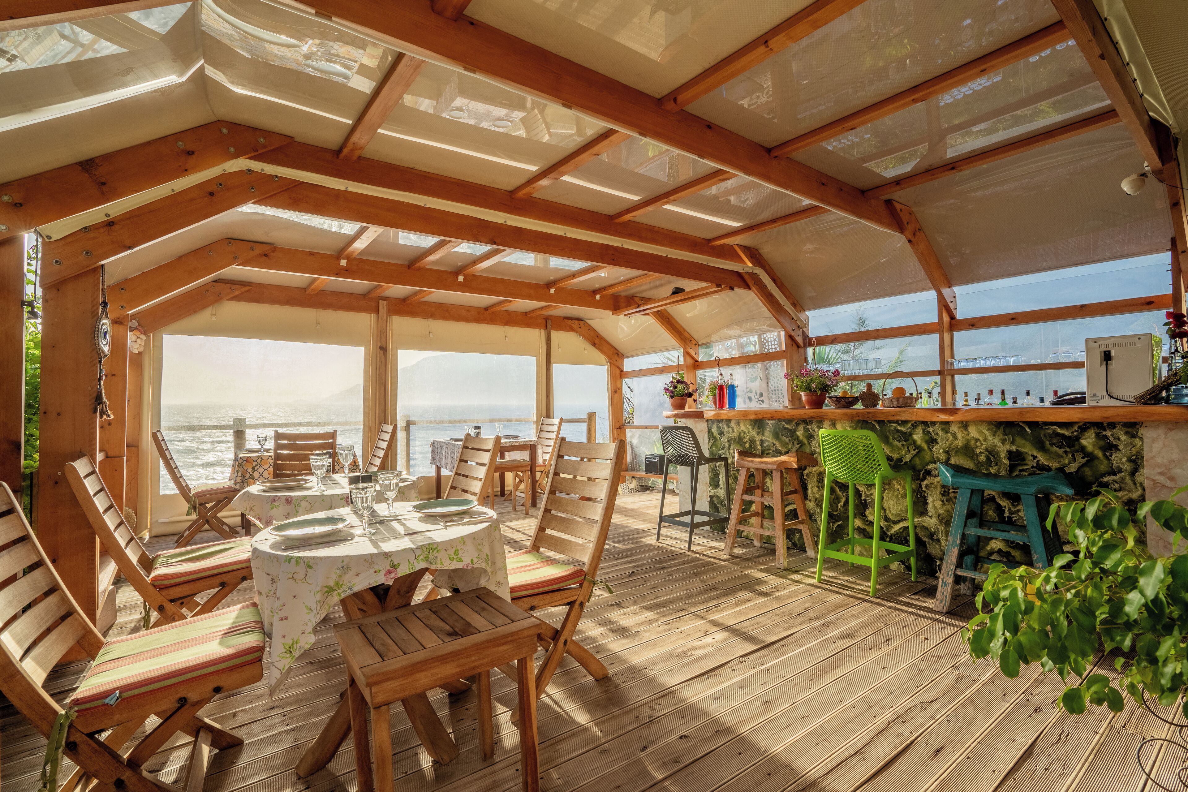 Une terrasse extérieure couverte, aménagée avec des meubles en bois, une table et un coin bar.