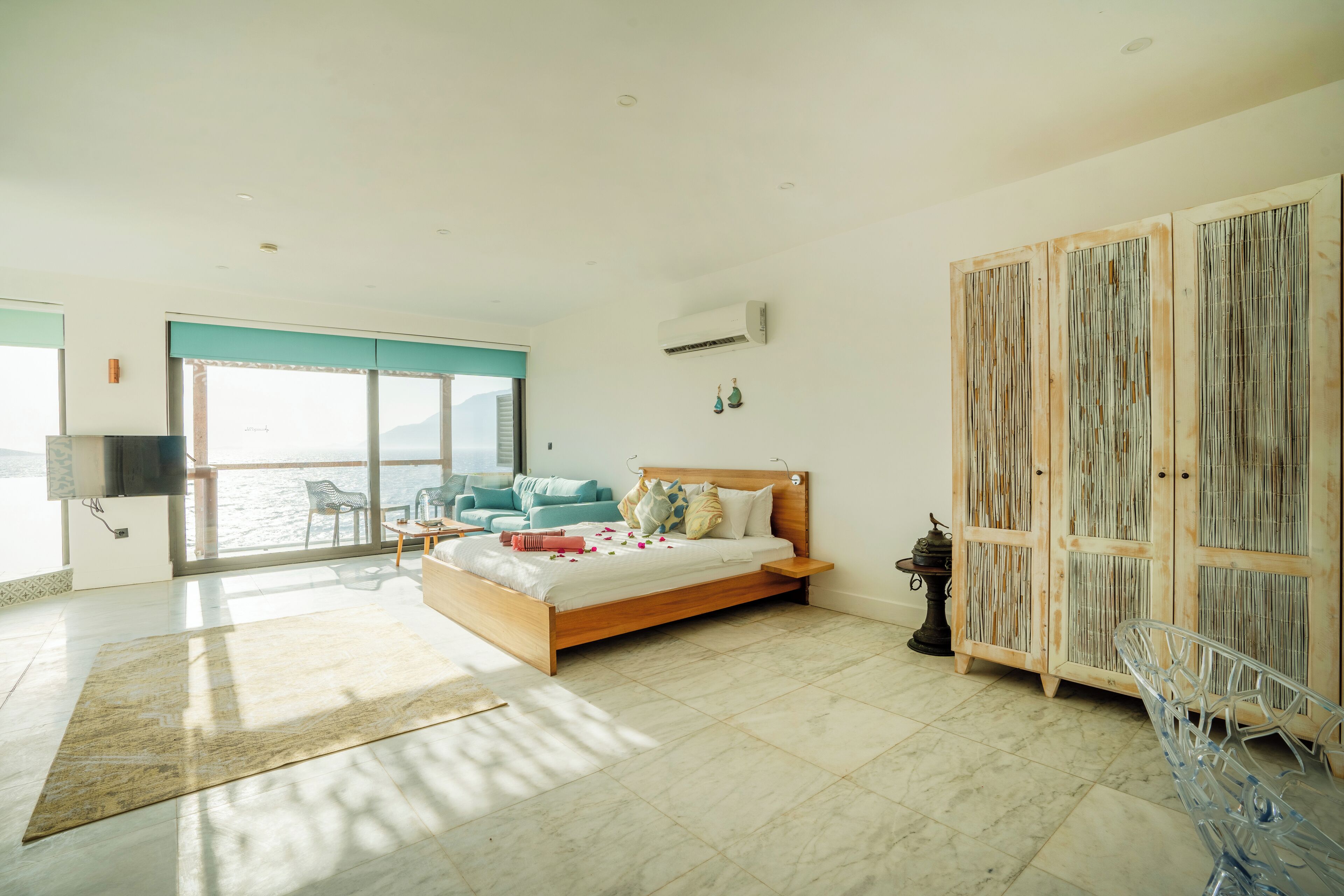 Une chambre spacieuse avec un grand lit, une vue sur la mer, une armoire en bois et une salle de bain moderne.