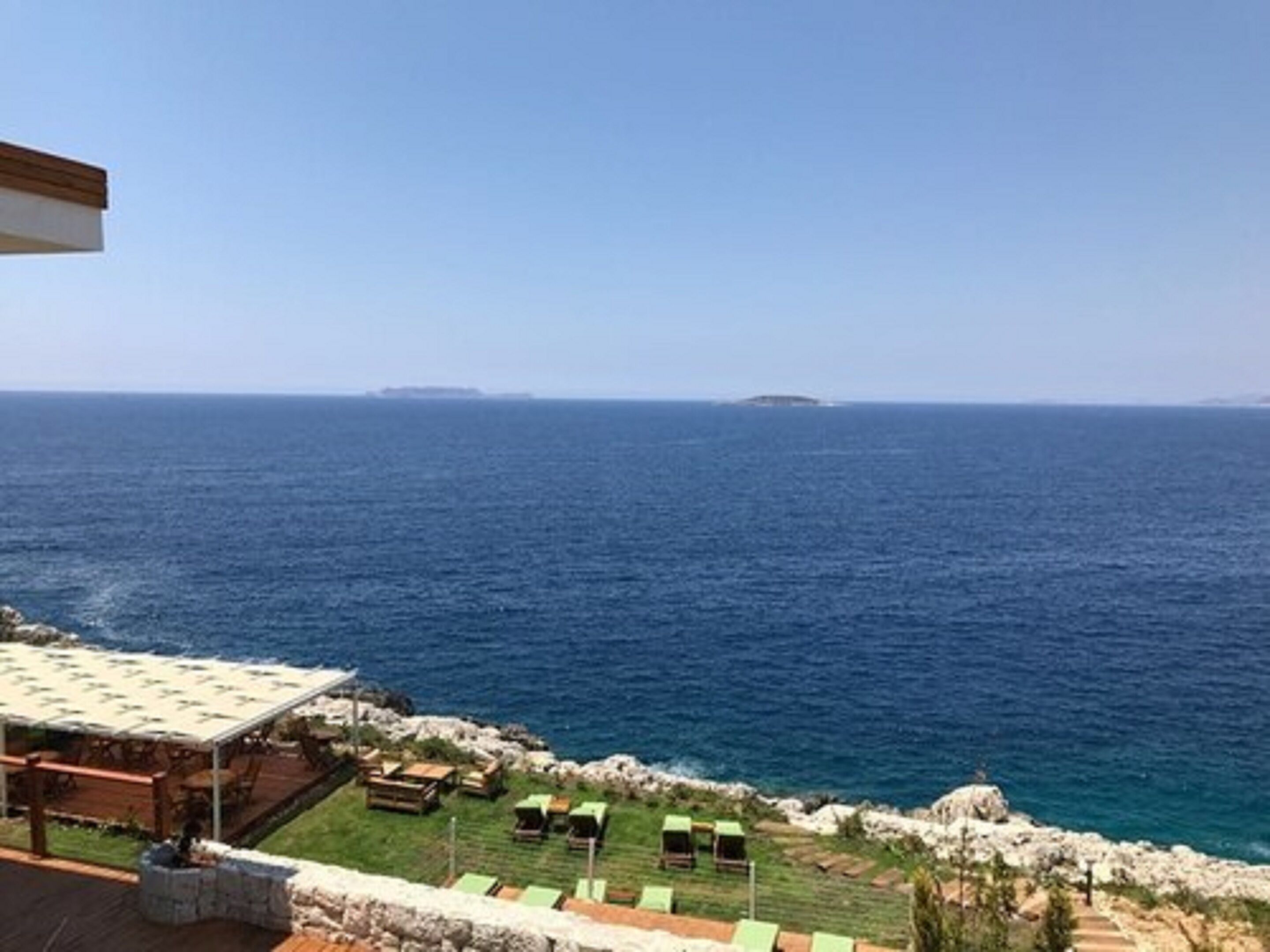 Una propiedad costera con patio, mobiliario exterior y vistas al mar.