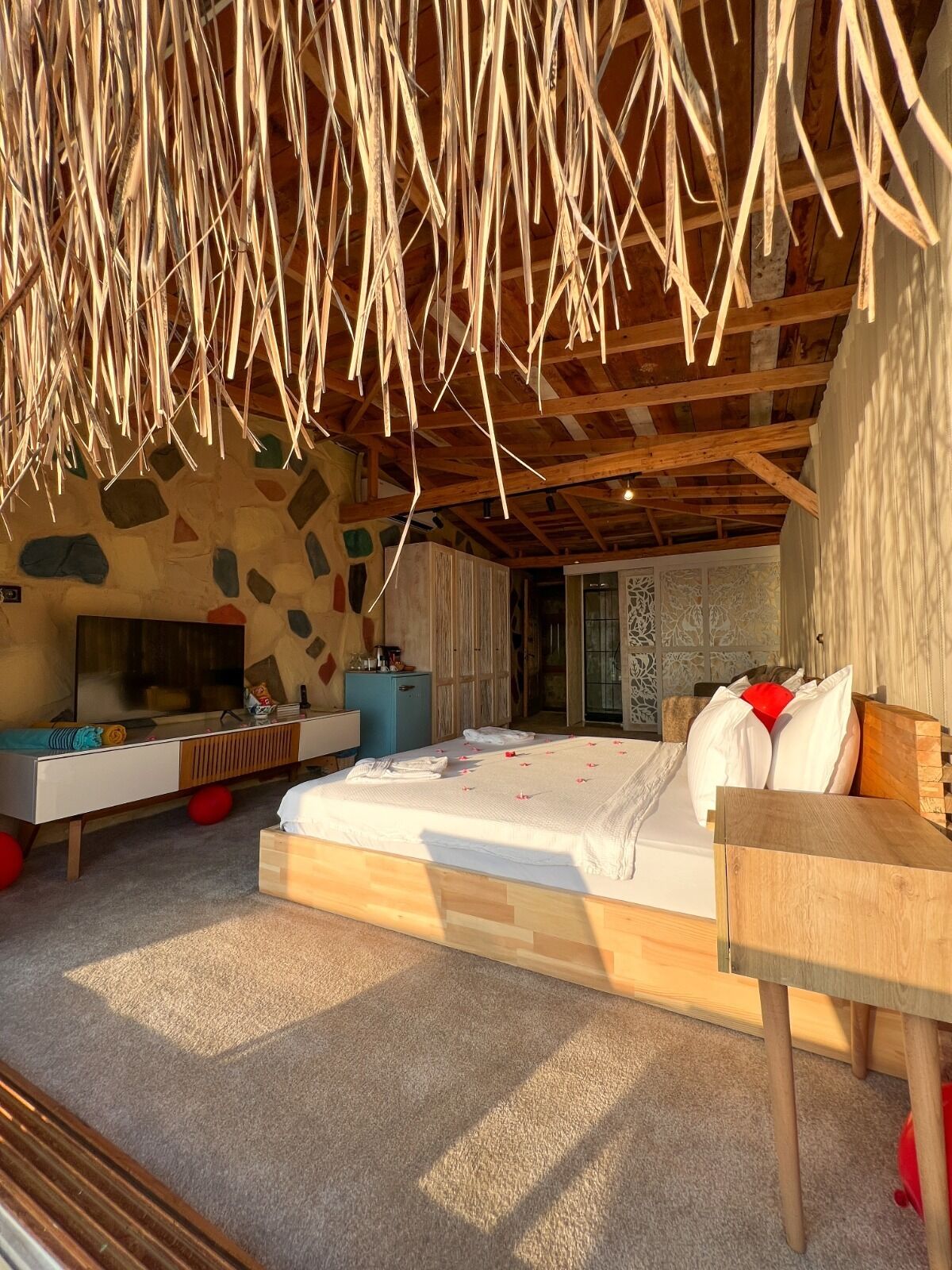 Un dormitorio moderno con una cama grande, un escritorio de madera y una pared de piedra.