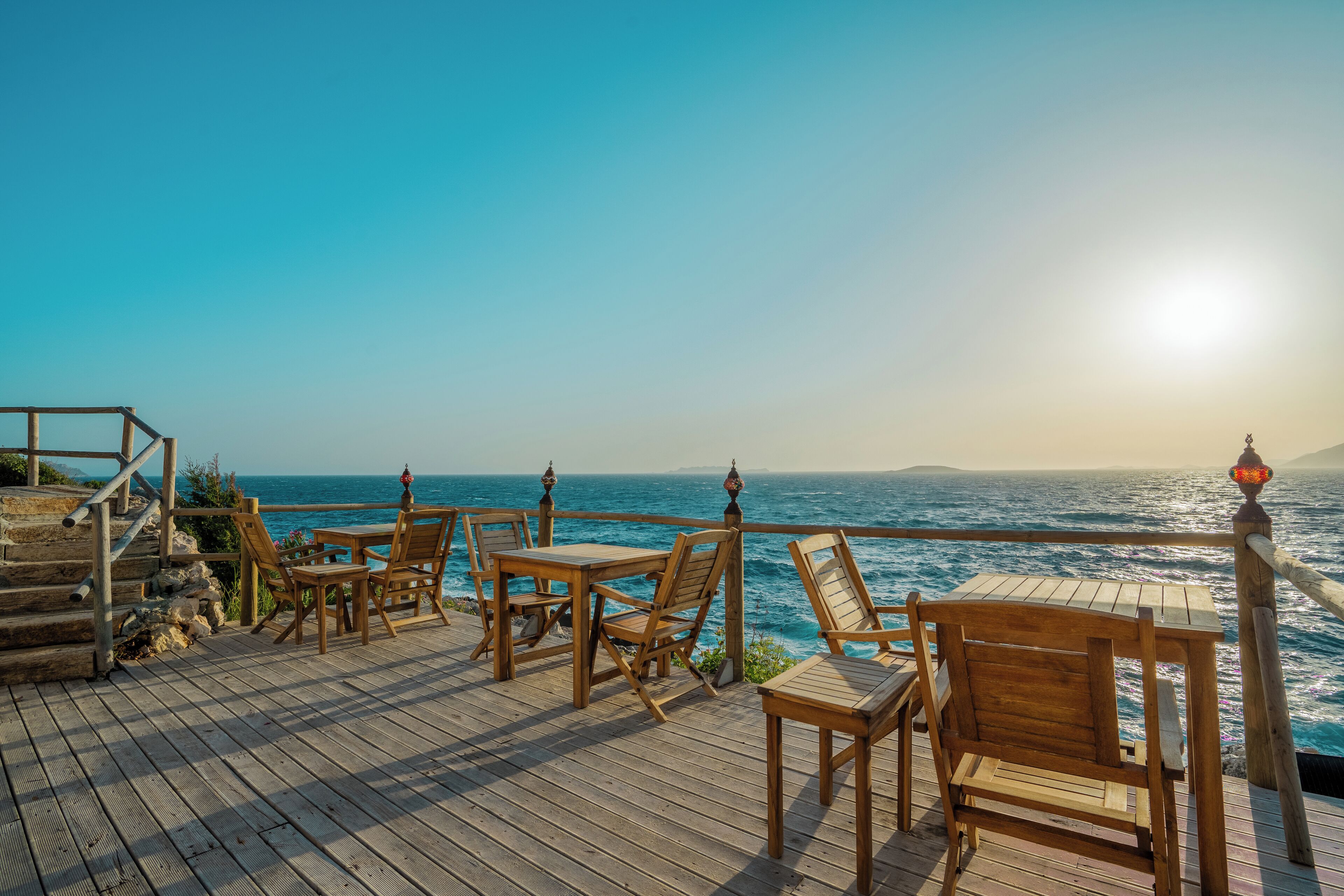 A wooden deck with outdoor seating overlooking the ocean.