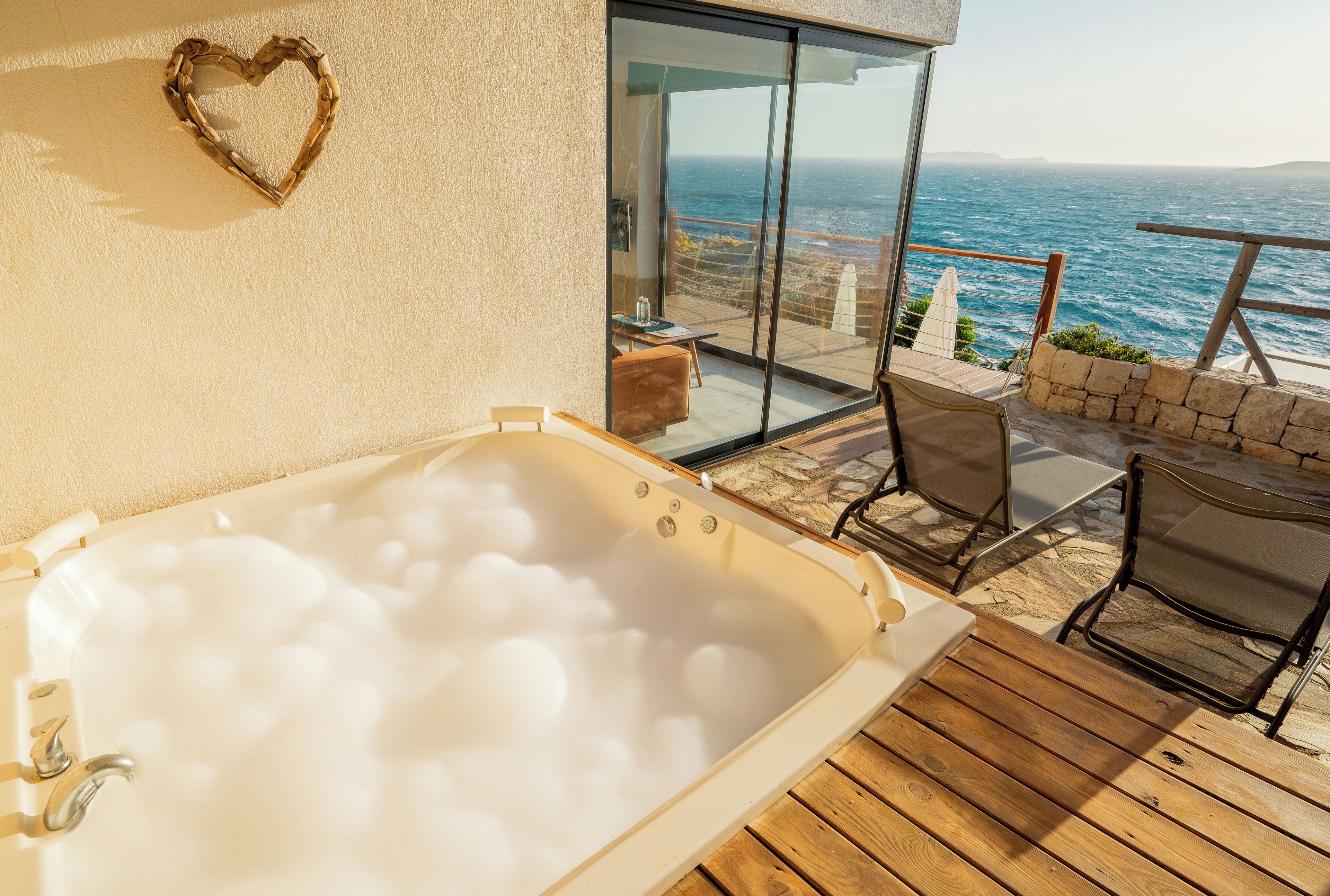 A spa area with a hot tub, wooden deck, and a view of the sea.