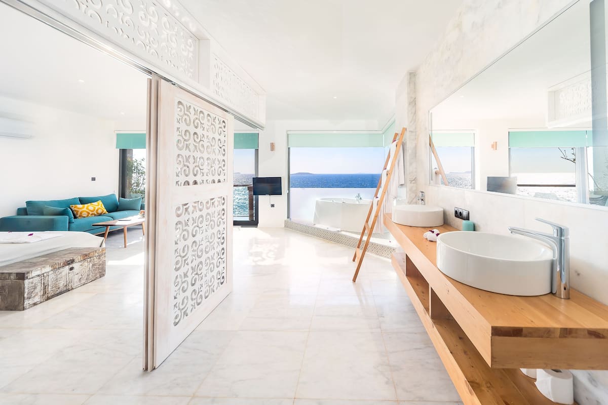 Un baño moderno con una bañera grande, un tocador de madera y vistas al mar.