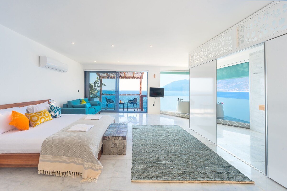 Una habitación de hotel moderna con cama, sofá y balcón con vista al mar.