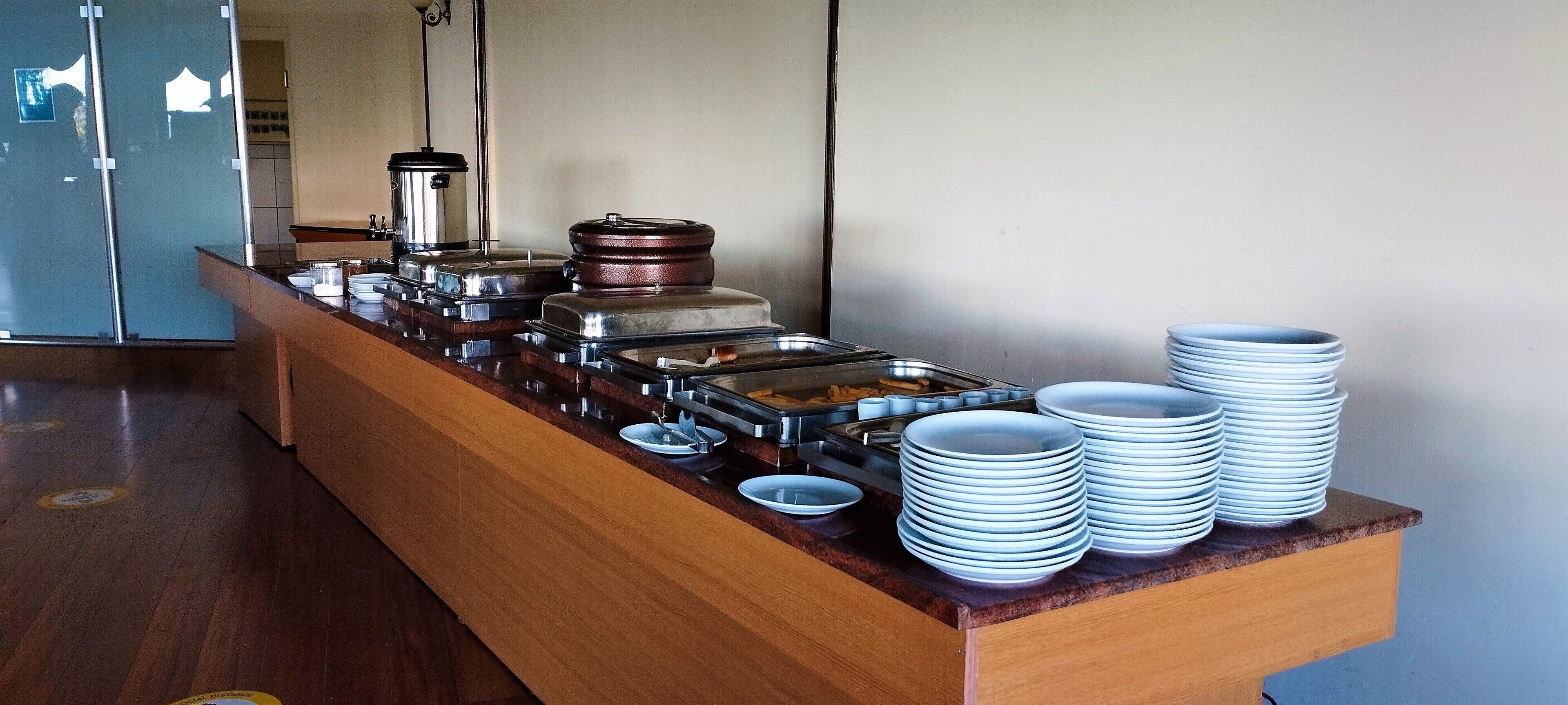 A buffet setup with various food containers and stacked plates.