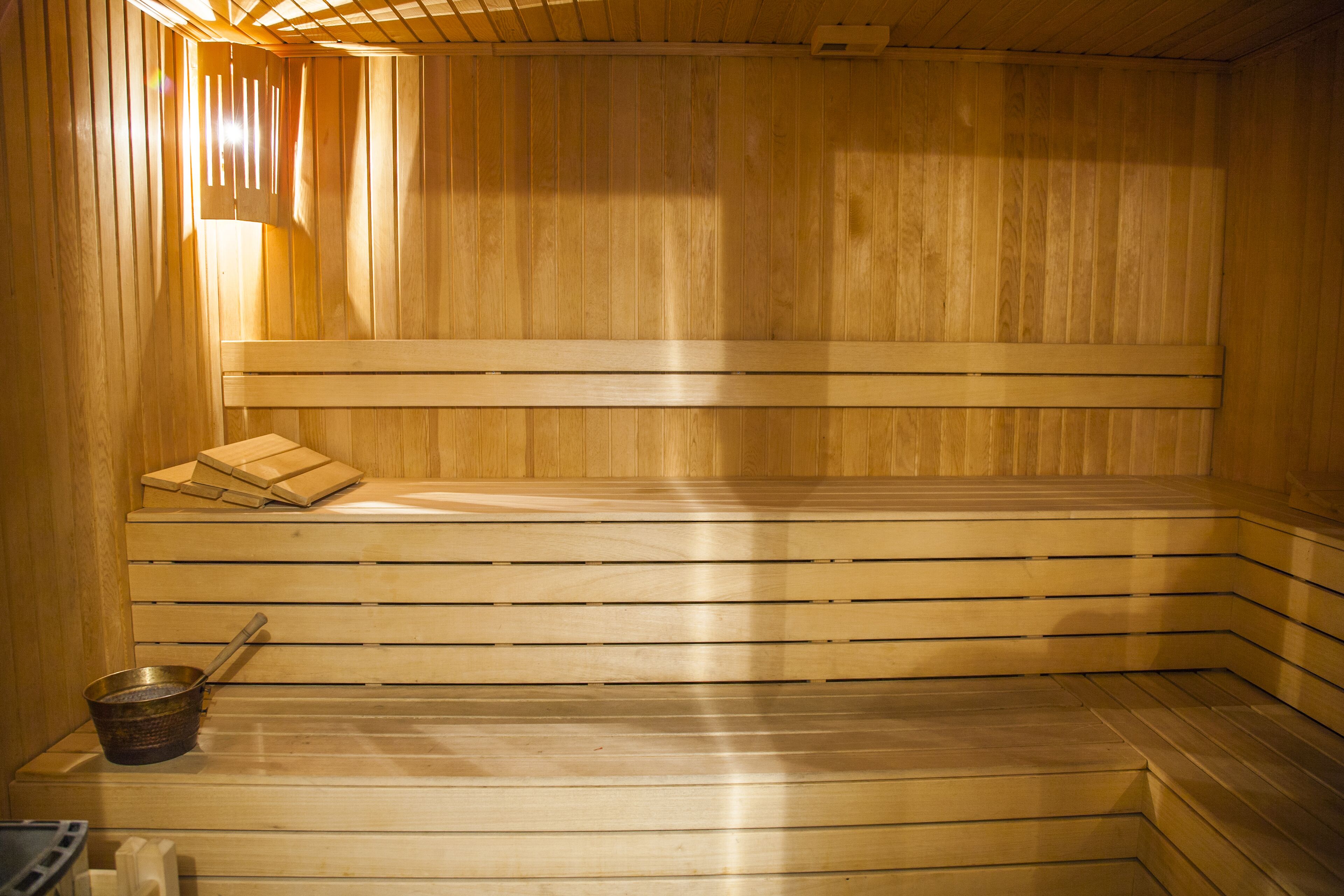 Una sauna con bancos de madera y un banco con toallas.