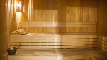 Una sauna con bancos de madera y un banco con toallas.
