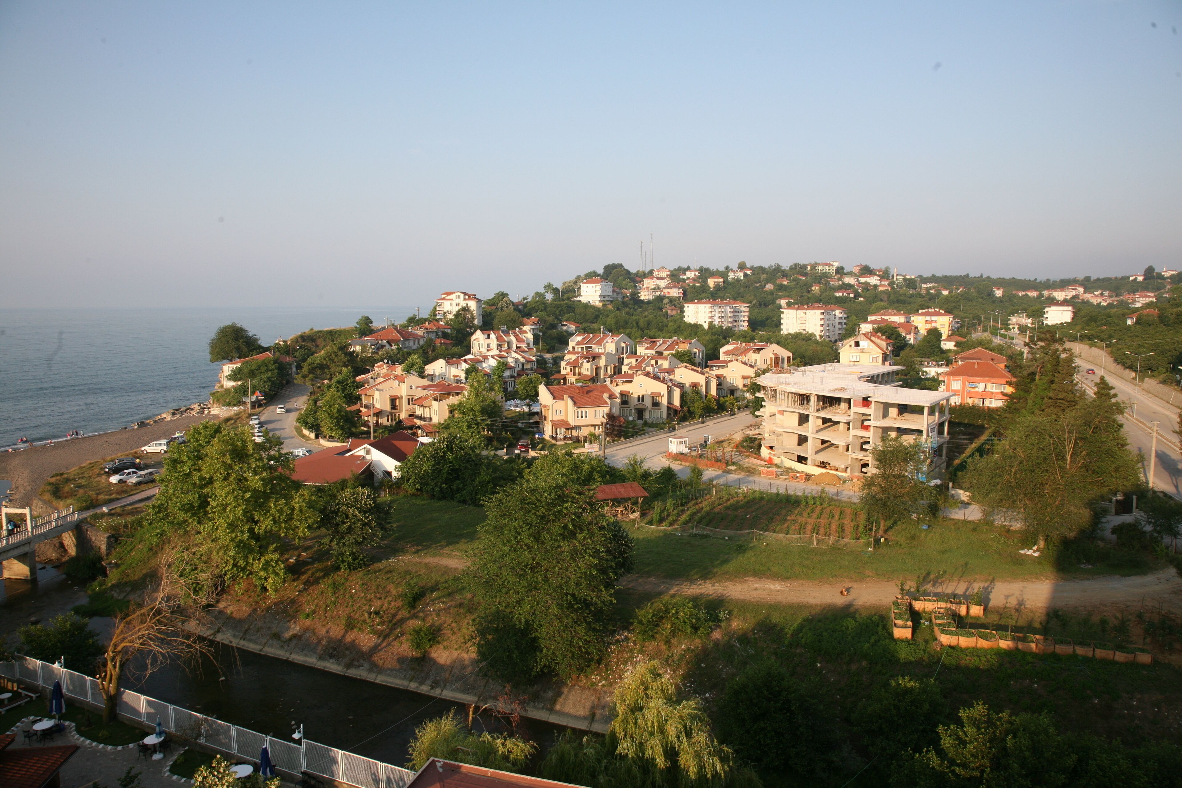 Une ville côtière où se côtoient des immeubles d’habitation, dont certains sont surmontés de toits rouges, et un pont bien visible qui la relie à la terre ferme.