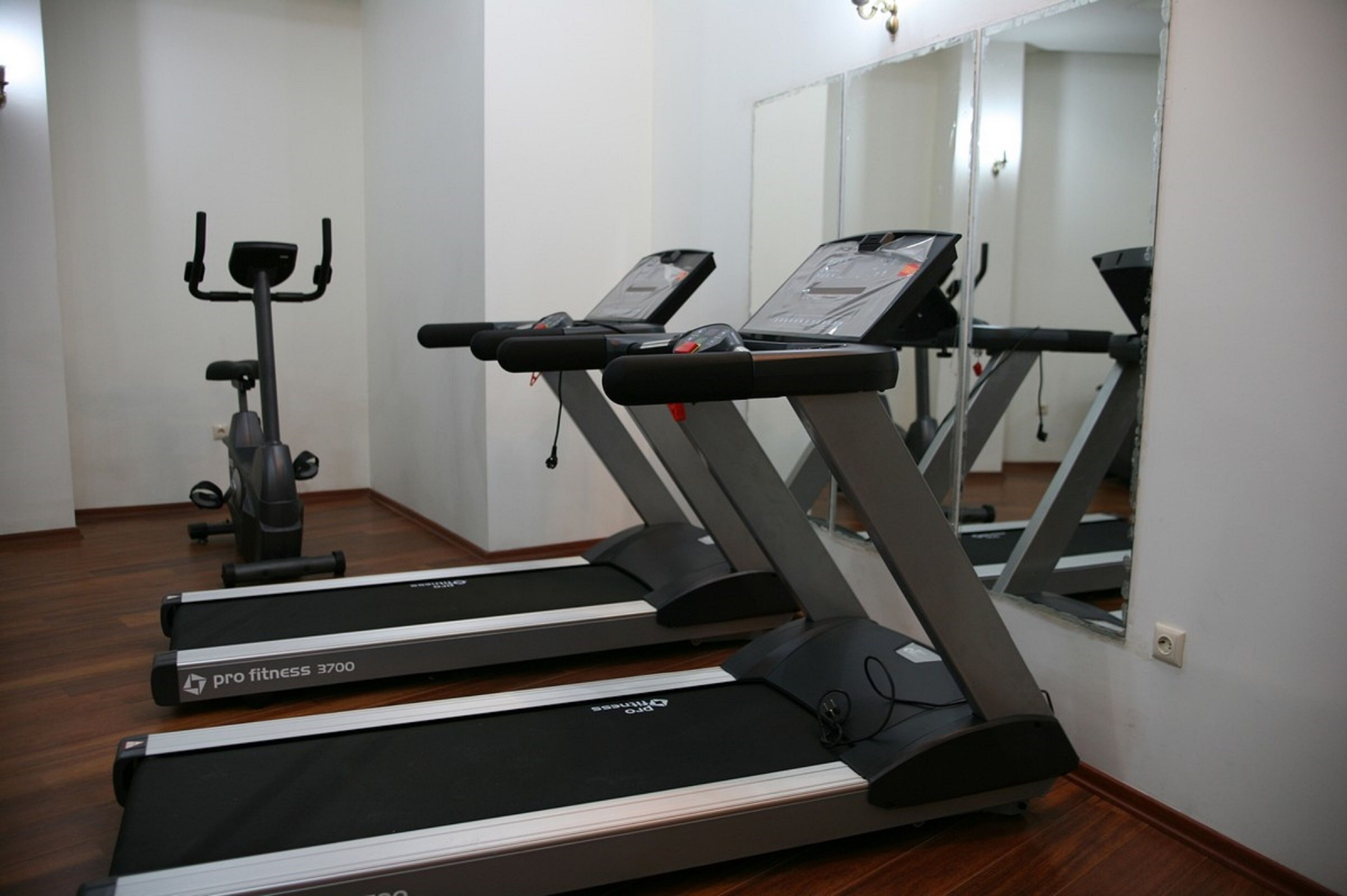 A gym with treadmills, a stationary bike, and a mirror reflecting the room.