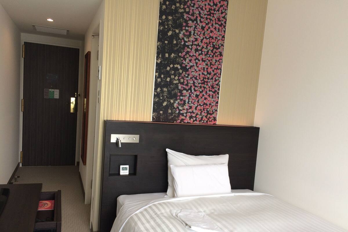 Een hotelkamer met een bed, een bureau en een deur.