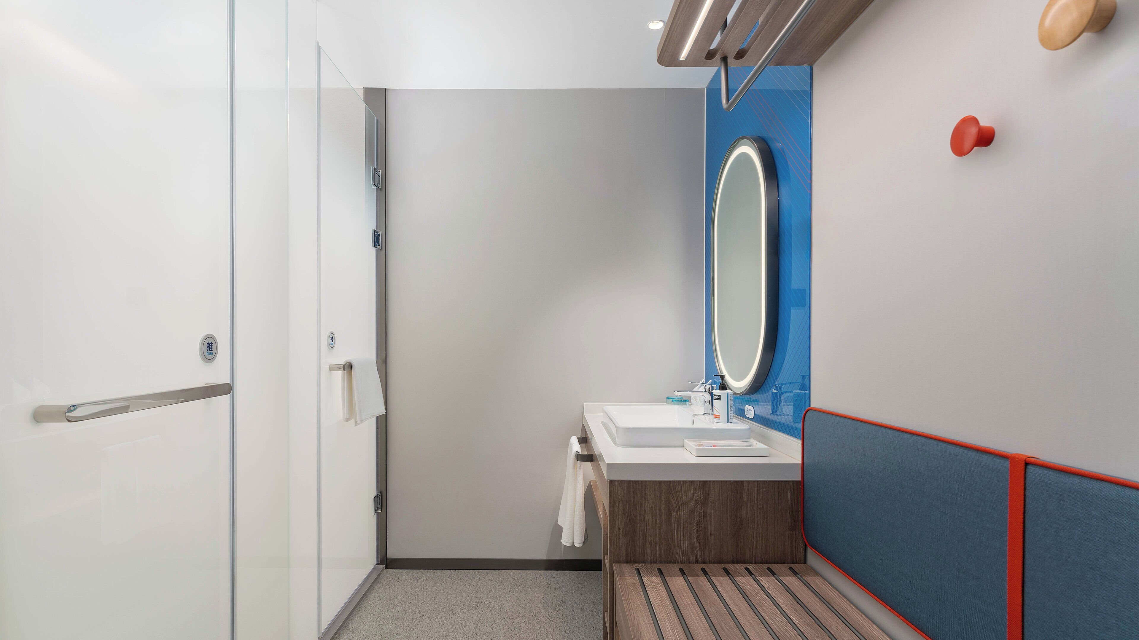 A modern bathroom with a glass shower door, a sink with a mirror, and a towel rack.