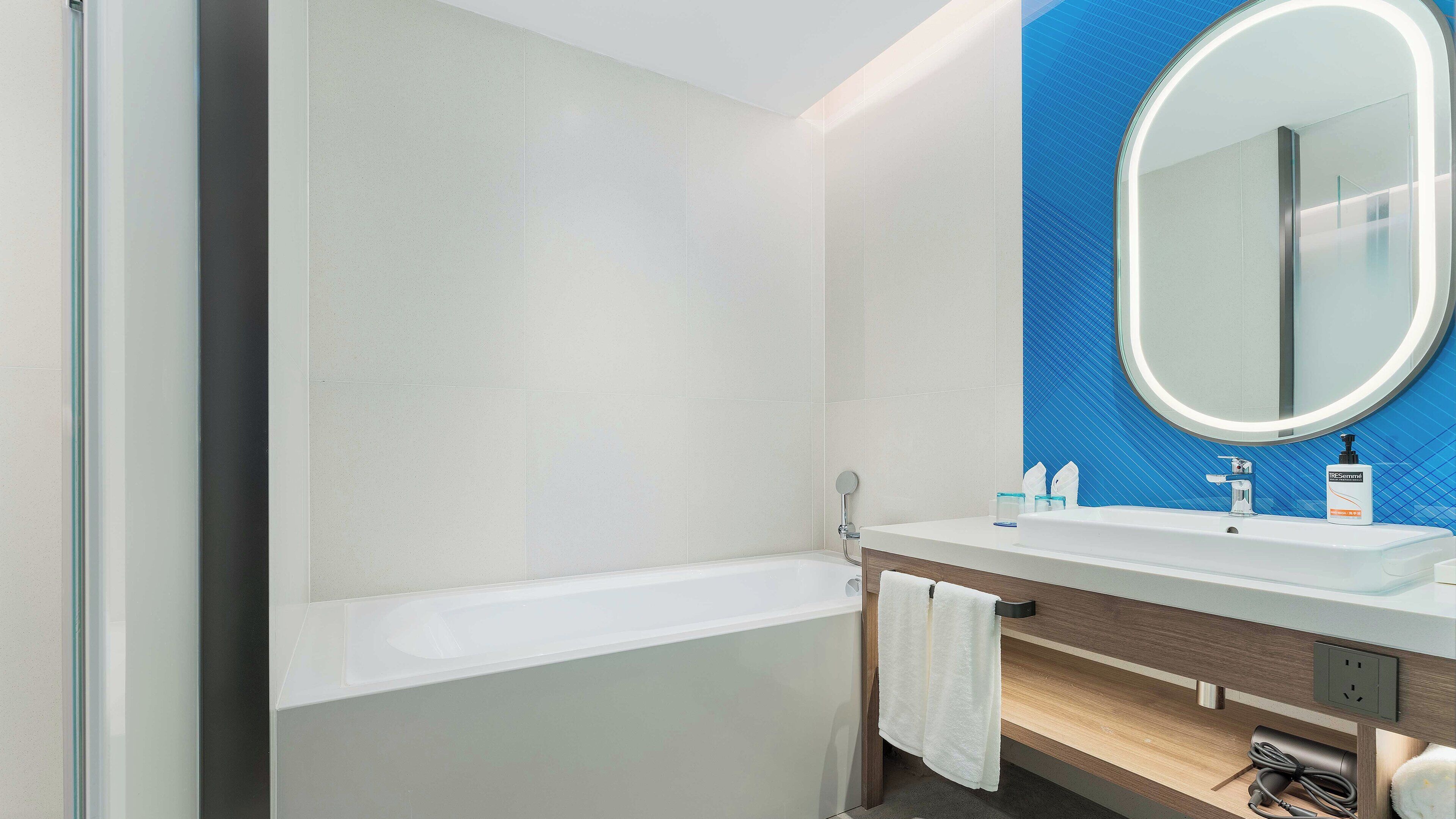 A modern bathroom with a bathtub, a sink, and a mirror.