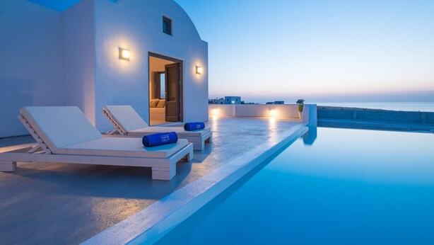 Un área junto a la piscina con sillones de descanso y vistas al mar.