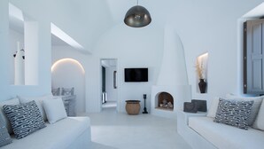 Una sala de estar moderna con un conjunto de sofás, una chimenea y un televisor montado en la pared.