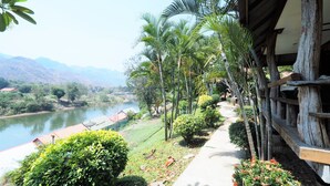 A pathway lined with greenery and a river in the background. - Khaothone River View Resort (Sai Yok)