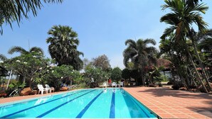 A swimming pool with blue lane markings, surrounded by palm trees and a brick walkway. - Khaothone River View Resort (Sai Yok)