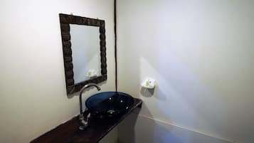 Un baño con tocador de madera oscura, un lavabo negro y un espejo con marco de madera.