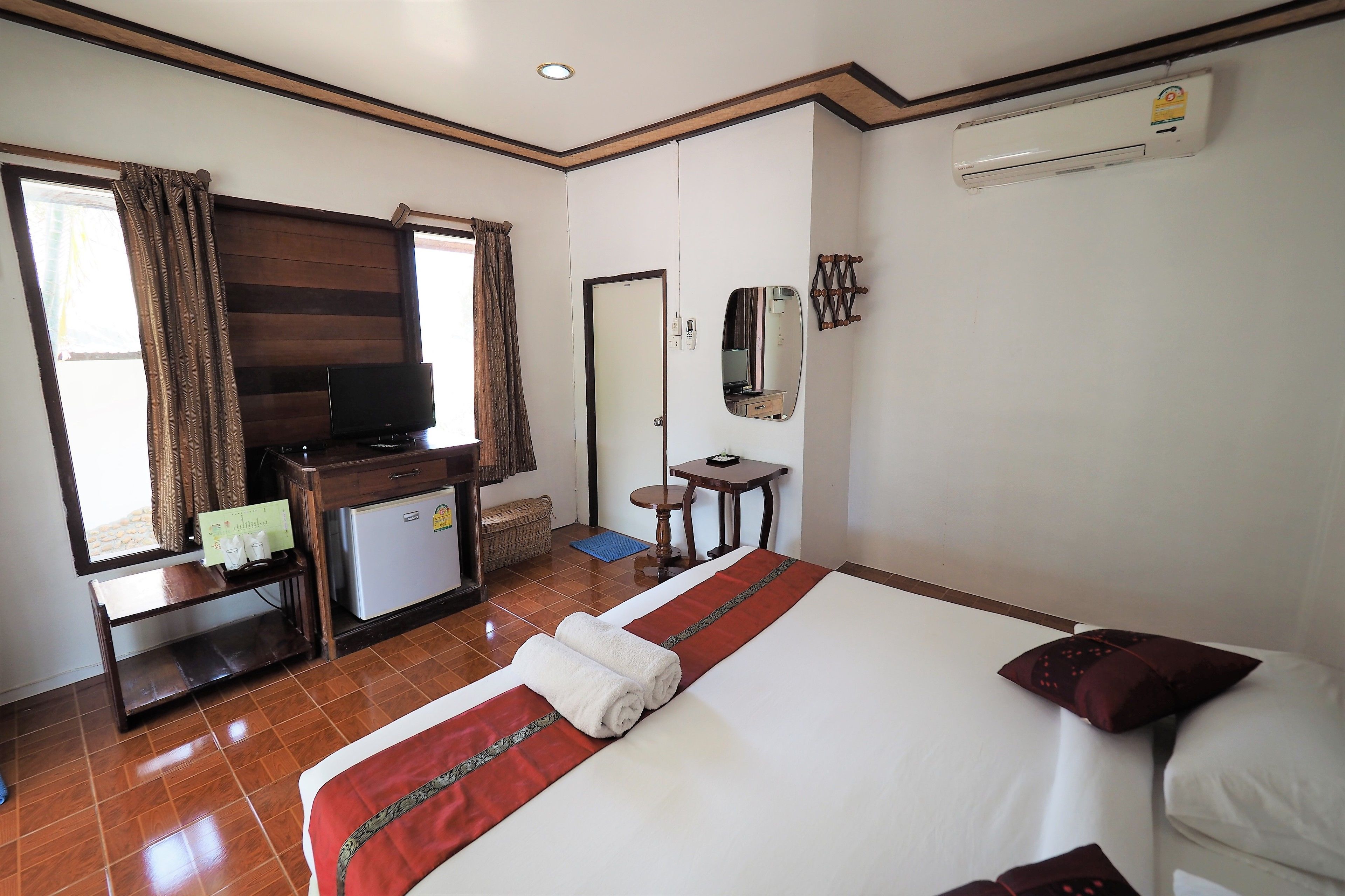 A hotel room with a bed, a TV, a desk, and a small refrigerator.