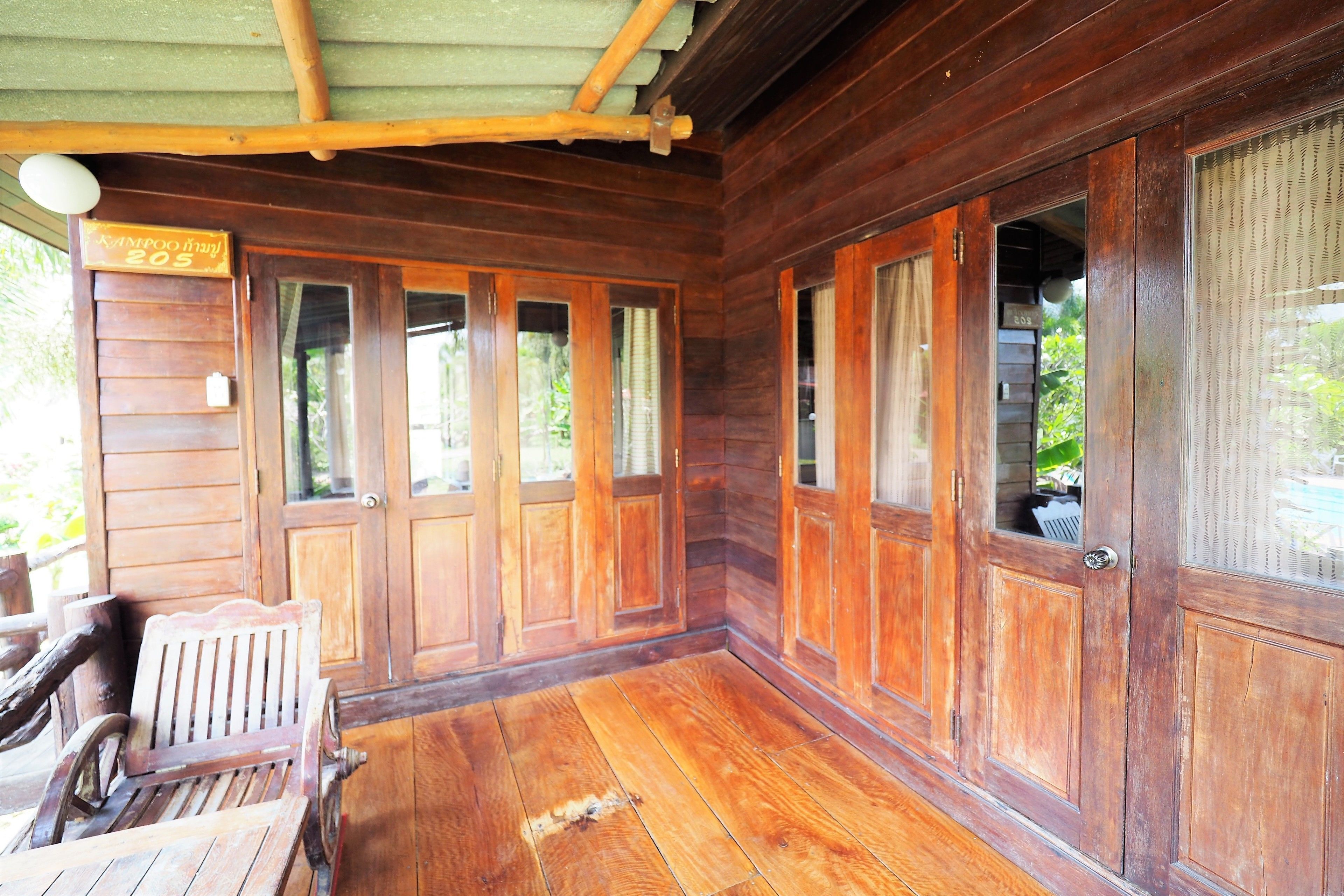 Una cabaña de madera con un porche, puertas de madera y un banco.