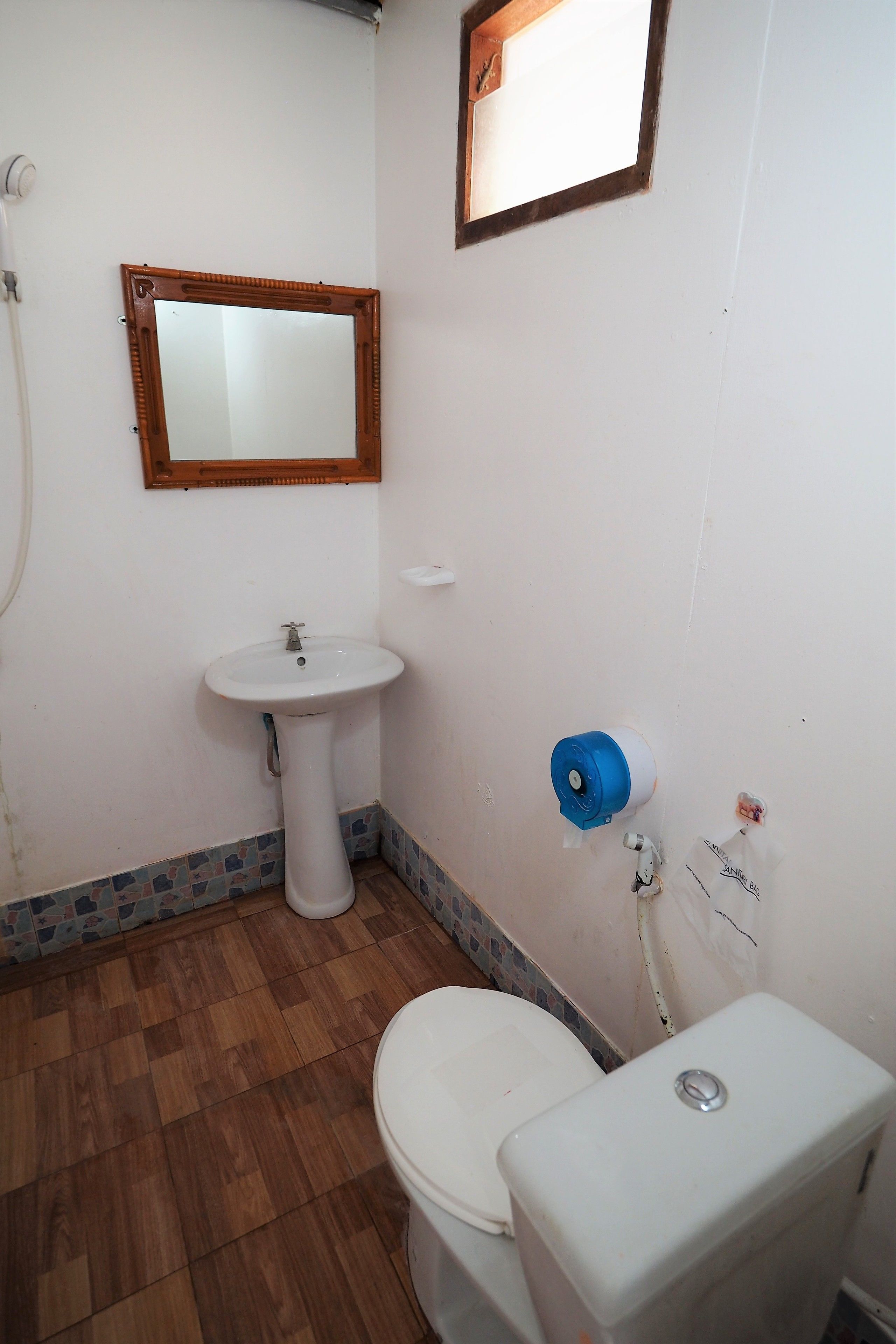 A bathroom with a wooden floor, white sink, and toilet.