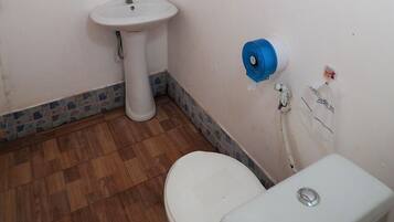 A bathroom with a wooden floor, white sink, and toilet.