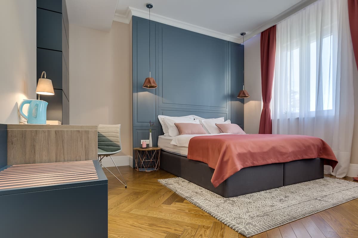 A modern bedroom with a bed, bedside lamps, a nightstand, a chair, and a desk.