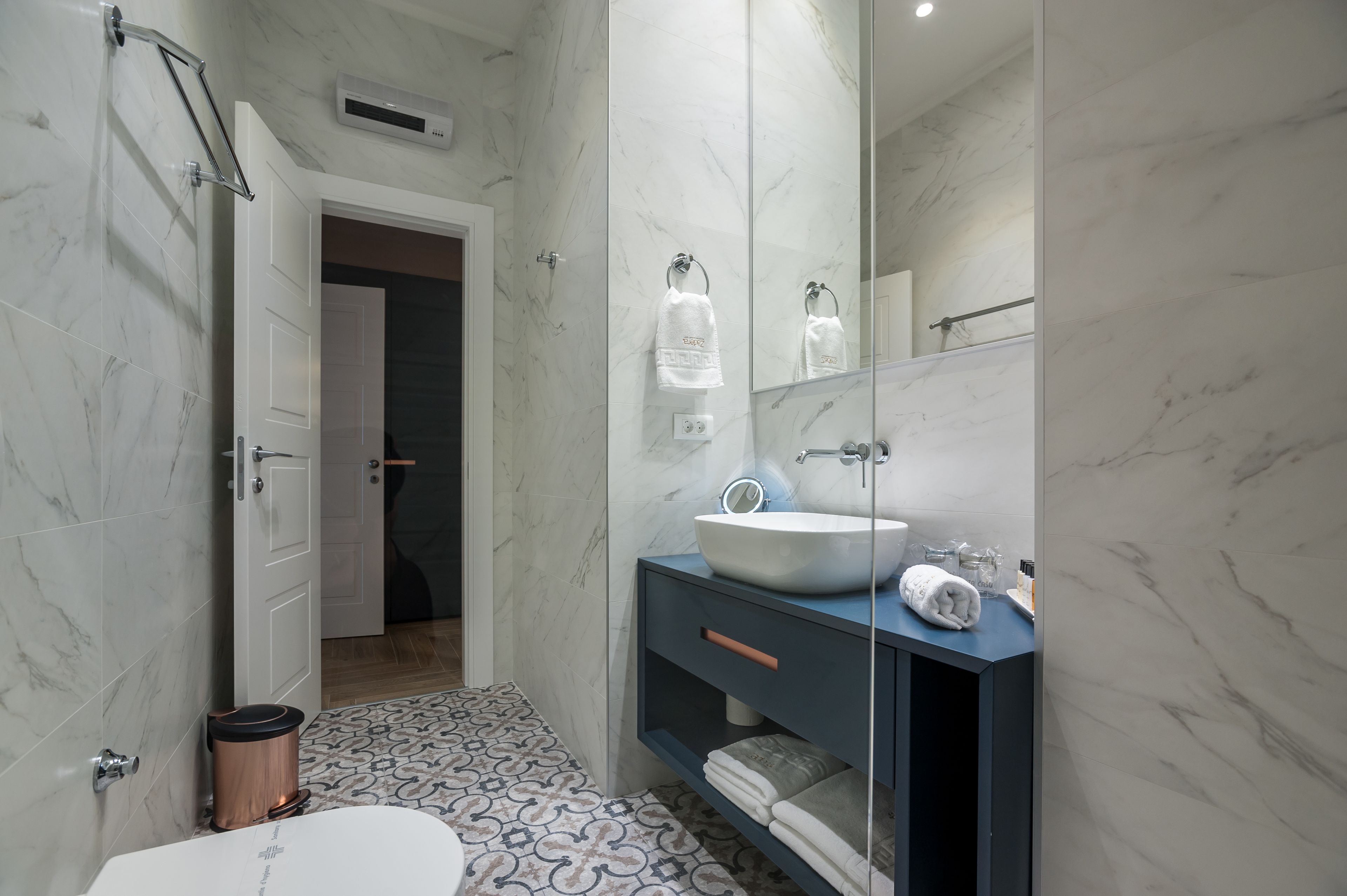 A modern bathroom with a white sink, dark vanity, and patterned floor tiles.