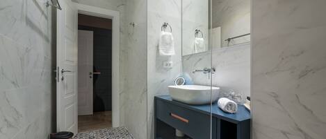 A modern bathroom with a white sink, dark vanity, and patterned floor tiles.