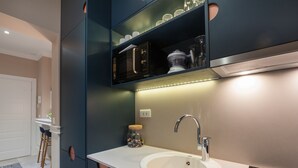 Une cuisine moderne avec un évier blanc, un robinet en acier inoxydable et des meubles de couleur sombre.
