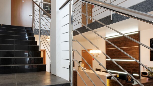 Una escalera moderna con barandillas de metal y un mostrador de recepción de madera.