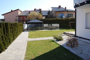 A residential property with a paved pathway, a well-maintained lawn, and a glass greenhouse structure.