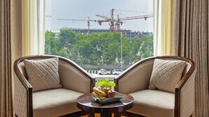 Una habitación con dos sillones mirando a una ventana con vista a una obra en construcción.